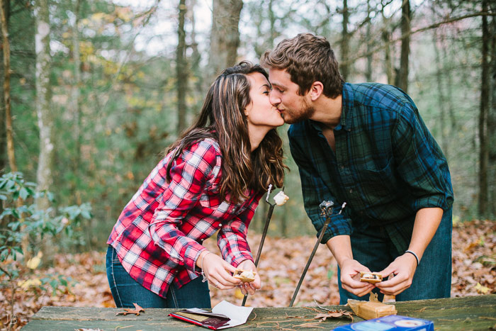 engagement session in the woods, surrounding a fire with smores and flannel in autumn