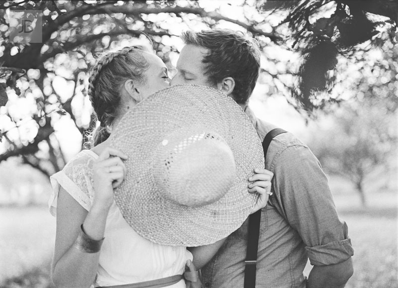 dreamy vintage engagement in an orchard staring at camera black and white film low contrast