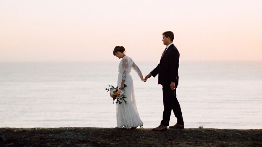 bride and groom walking on beach bluff at sunset Monterrey Bay California