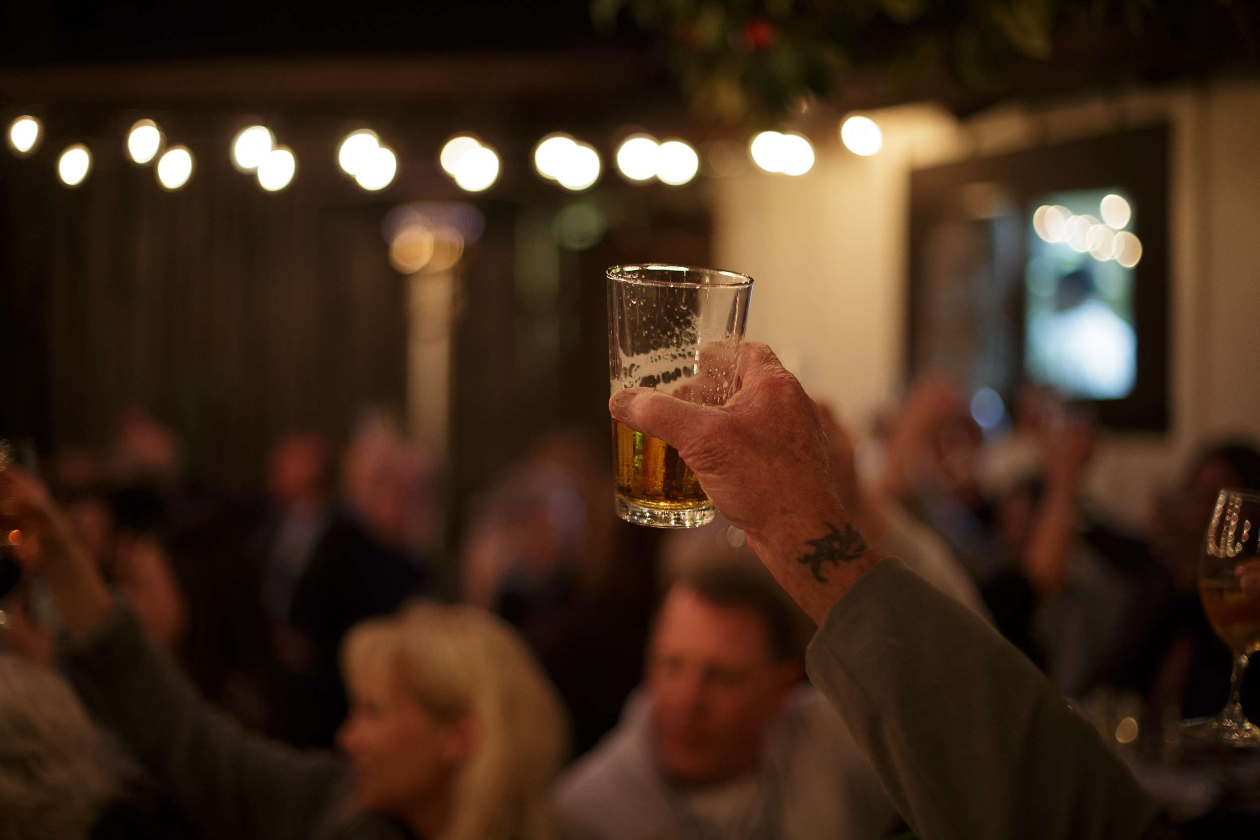 hand toasting with a half full glass of beer at big sur bakery in big sur california