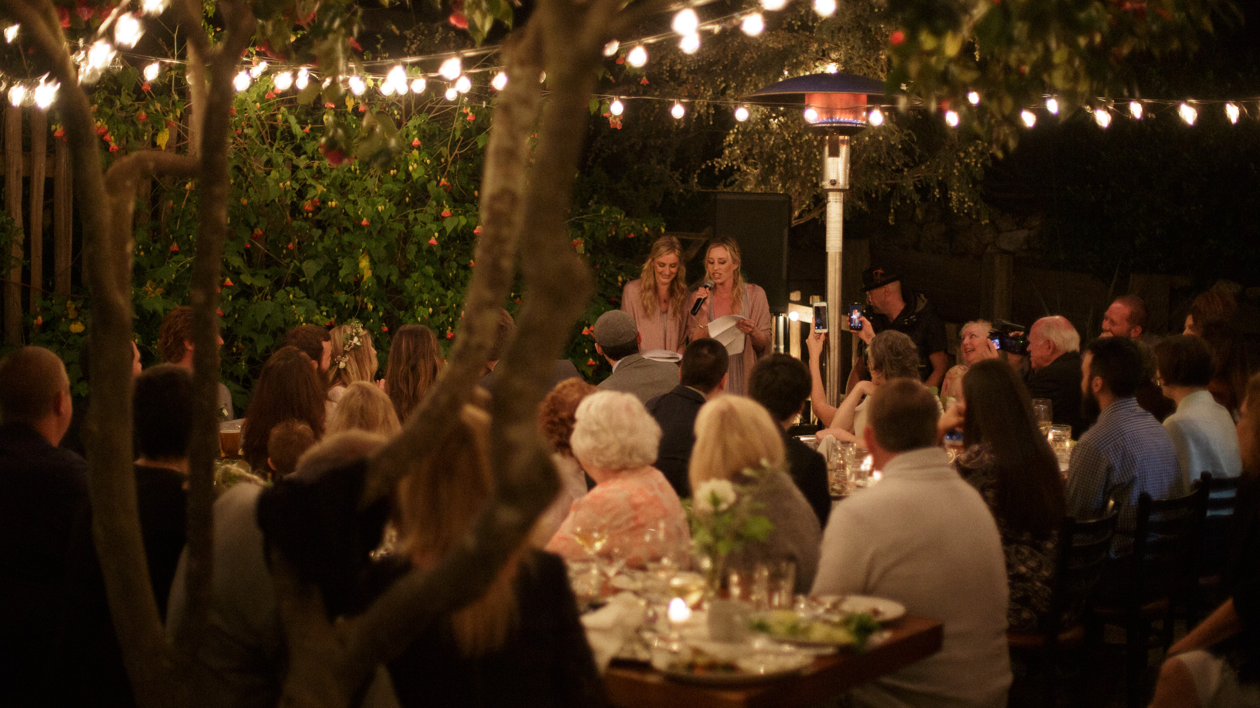 bridesmaids give a toast in wide angle documentary photograph during springtime wedding reception at big sur bakery patio