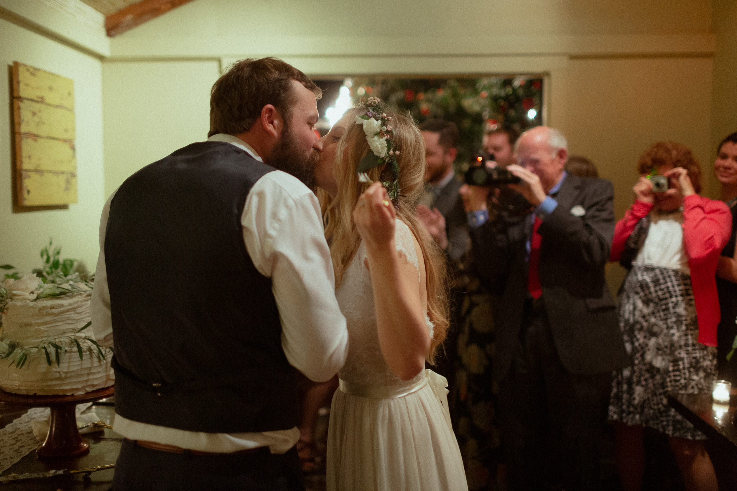 bride and groom kiss after feeding each other cake at wedding reception - documentary photography - unintrusive photographer