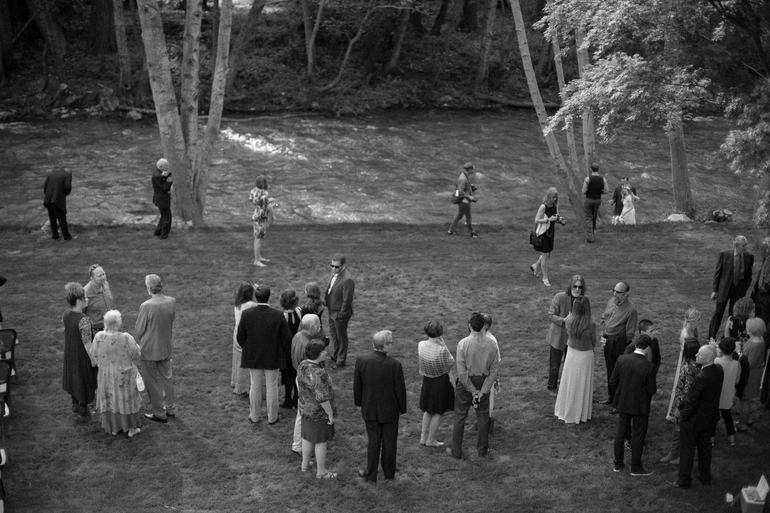 view from big sur river inn balcony with wedding guests gathered on lawn by the big sur river - big sur california wedding - laid back wedding in big sur california - fuji acros black and white film look