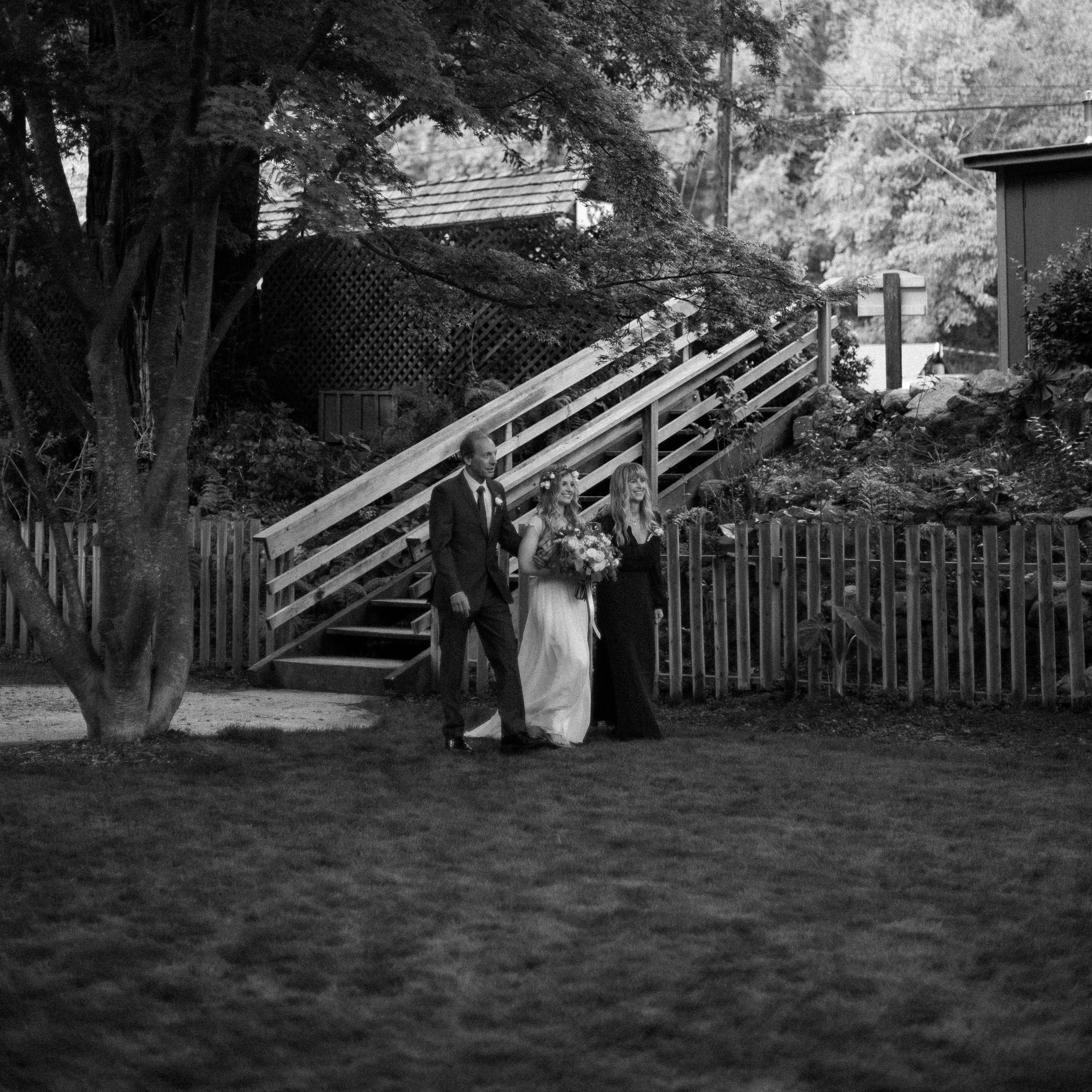 bride enters wedding ceremony with her parents - big sur california wedding - laid back wedding in big sur california - fuji acros black and white film look - documentary photography style