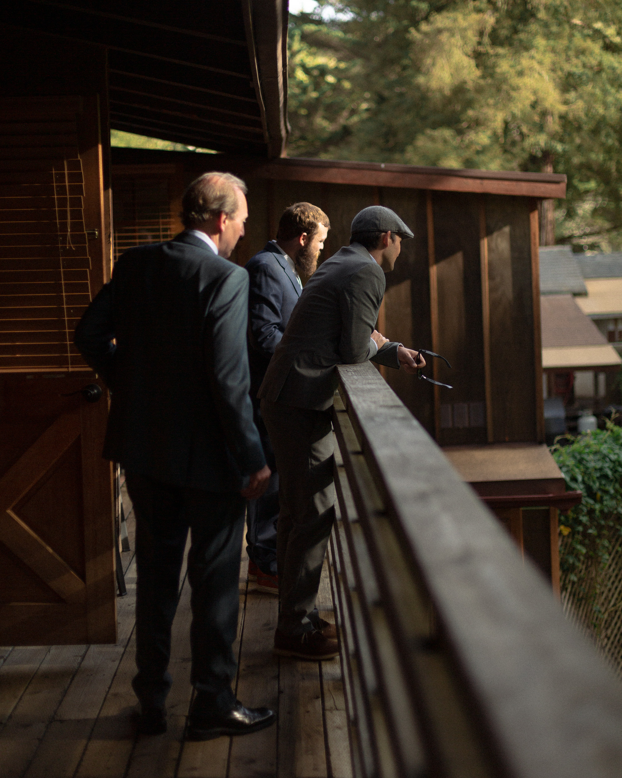 groom and groomsmen look towards big sur river from balcony deck of big sur river inn - big sur california wedding - laid back wedding in big sur california - fuji provia film look true to life colors