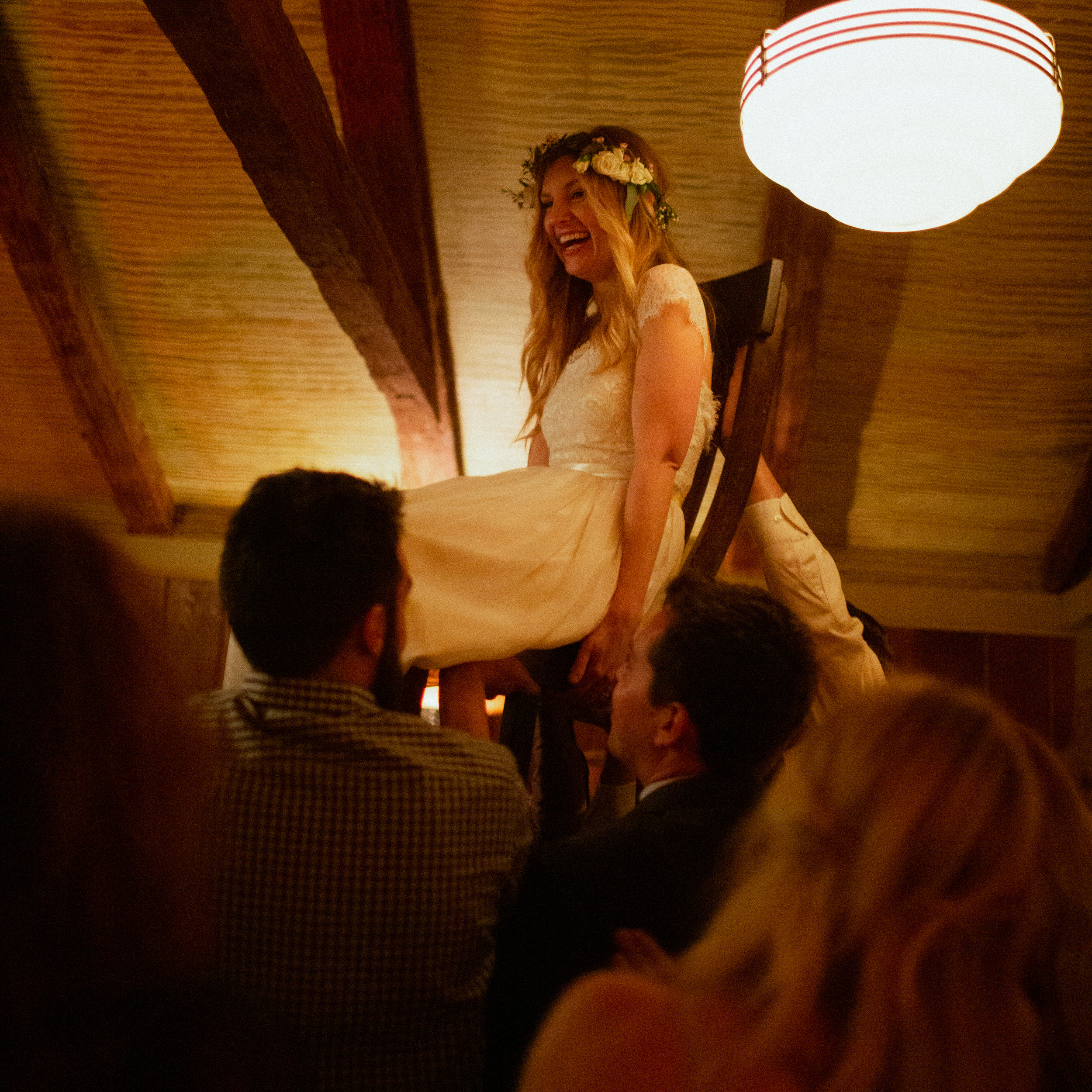 bride laughing as she is lifted up in chair during wedding reception at big sur bakery - documentary photographer